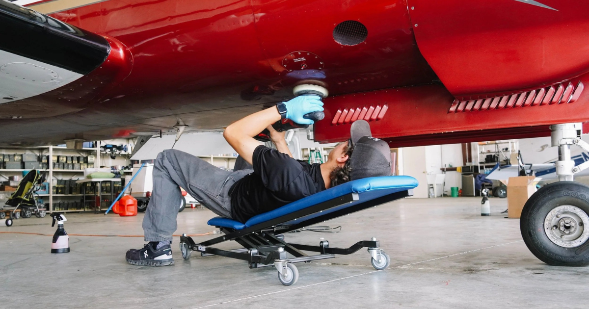 Técnico a polir a fuselagem de aeronave em hangar — detalhe profissional de aviação em ambiente costeiro, Madeira, Açores e Península Ibérica